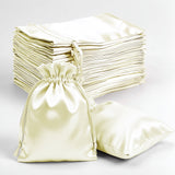 Satin drawstring pouches and pillowcases in cream color on white background