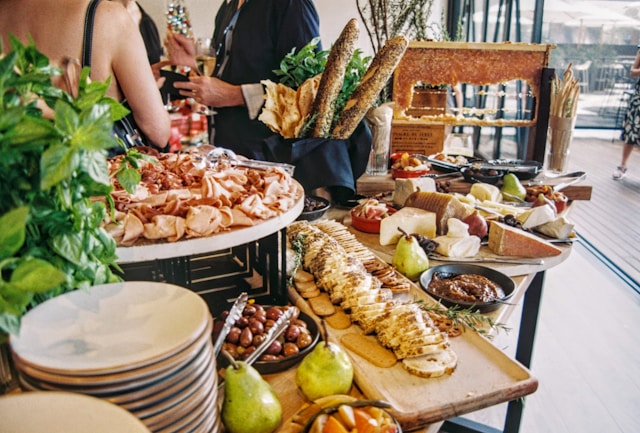 Elegant catering buffet table decorations featuring assorted meats, cheeses, and fresh greenery.