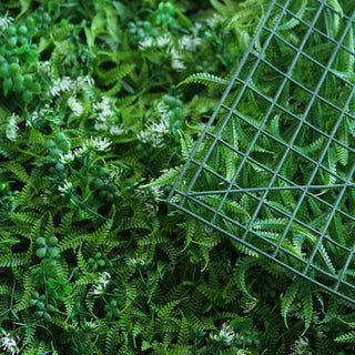 Artificial greenery mat with ferns and small flowers.