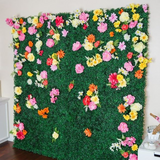 Artificial flower wall backdrop with colorful blooms on green foliage.