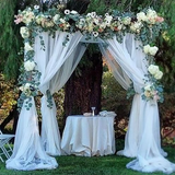 Wedding arch decorated with flowers and draped fabric.