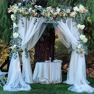 Wedding arch decorated with flowers and draped fabric.