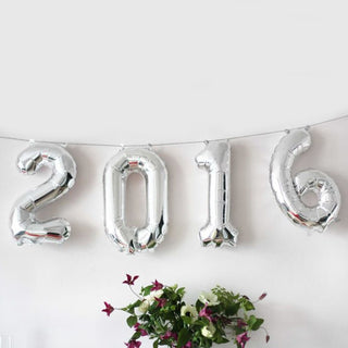 Silver 2016 balloon decoration with flowers in the background.