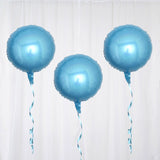 Three shiny blue balloons with ribbons on a white backdrop
