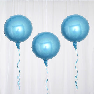 Three shiny blue balloons with ribbons on a white backdrop
