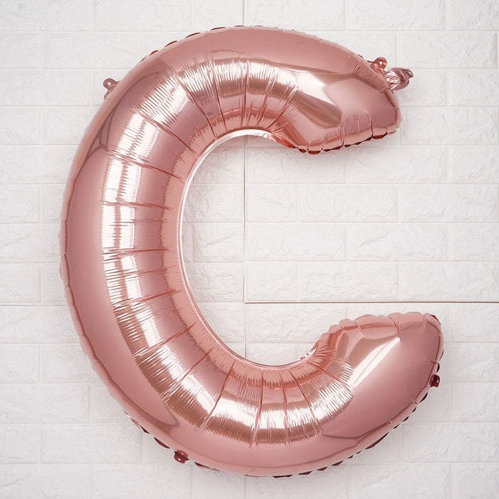 Rose gold foil letter "C" balloon against a white background.