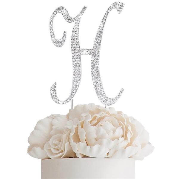 Elegant silver glitter "H" cake topper on white floral arrangement