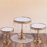 Gold mirrored cake stands with crystal accents on a wooden table.