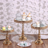 Gold dessert stands with glass tops and decorative lace, styled with treats and gifts.