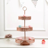 Three-tiered rose gold cake stand with decorative cutouts and colorful macarons.