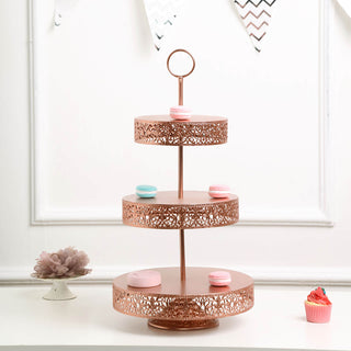 Three-tiered rose gold cake stand with decorative cutouts and colorful macarons.