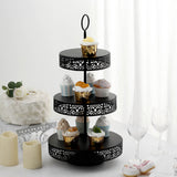 Black three-tier cupcake stand with decorative cutouts and assorted cupcakes.