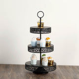 Black three-tier cake stand with decorative edges holding assorted cupcakes.