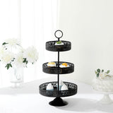Three-tiered black dessert stand with pastries on a white table.