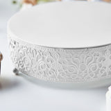 White decorative cake stand with intricate scrollwork design.