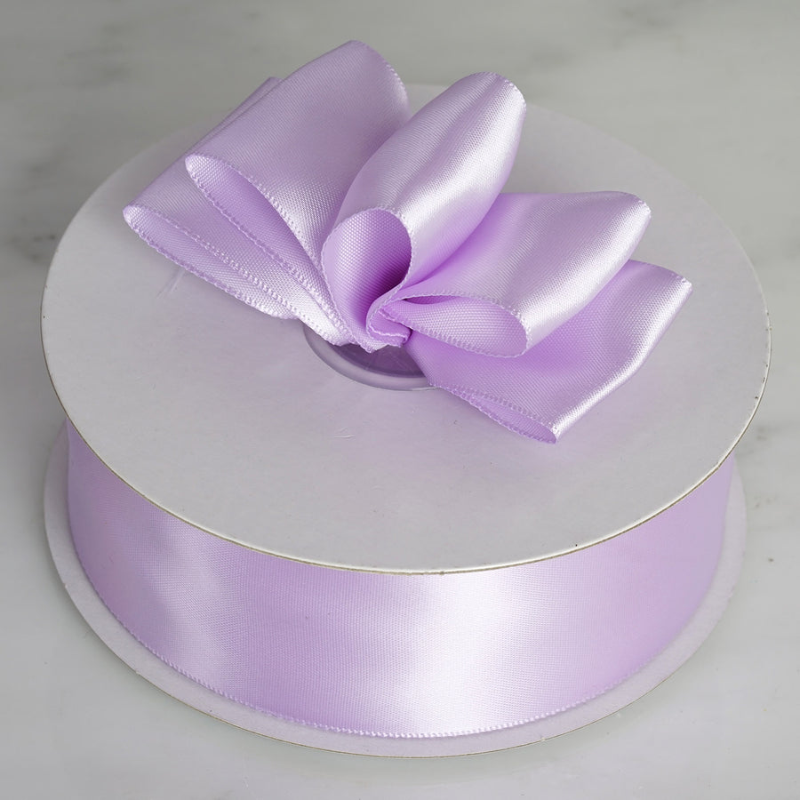 Purple satin ribbon with bow on spool, perfect for crafting and gift wrapping.