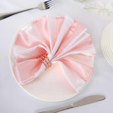 Elegant pink and white napkin with gold rings on a plate.