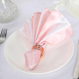 Pink and white satin napkin elegantly folded on a plate.