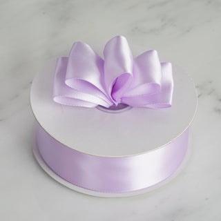 Purple satin ribbon on a spool with a bow on top.