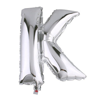 Silver foil letter K balloon on a plain background.