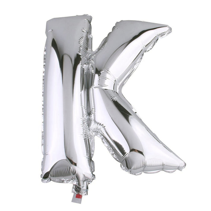 Silver foil letter K balloon on a plain background.