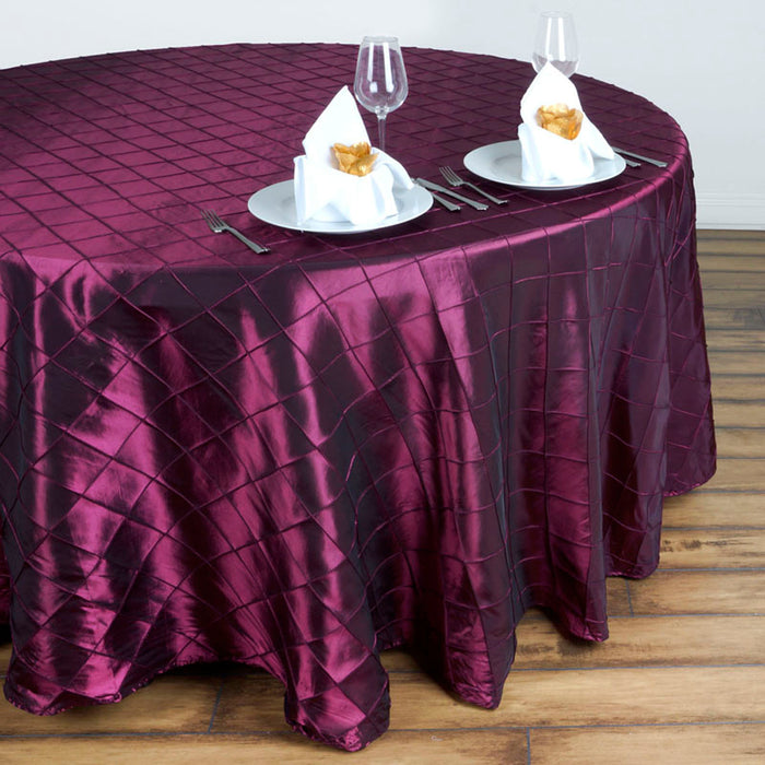 Burgundy tablecloth draped over a round table set for dining with plates and napkins.