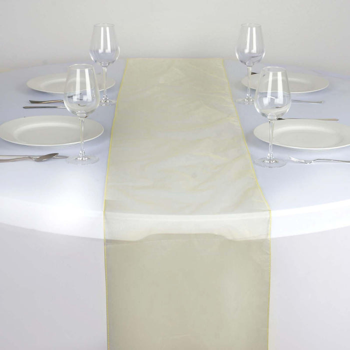 Sheer gold table runner on a round table set for dining #whtbkgd